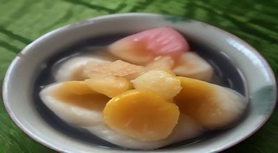 夏日阳光下一排色彩缤纷的手工冰棒整齐摆放在木质托盘上，背景为模糊的绿色植物，光线温暖自然，我爱吃冰棒主题配图